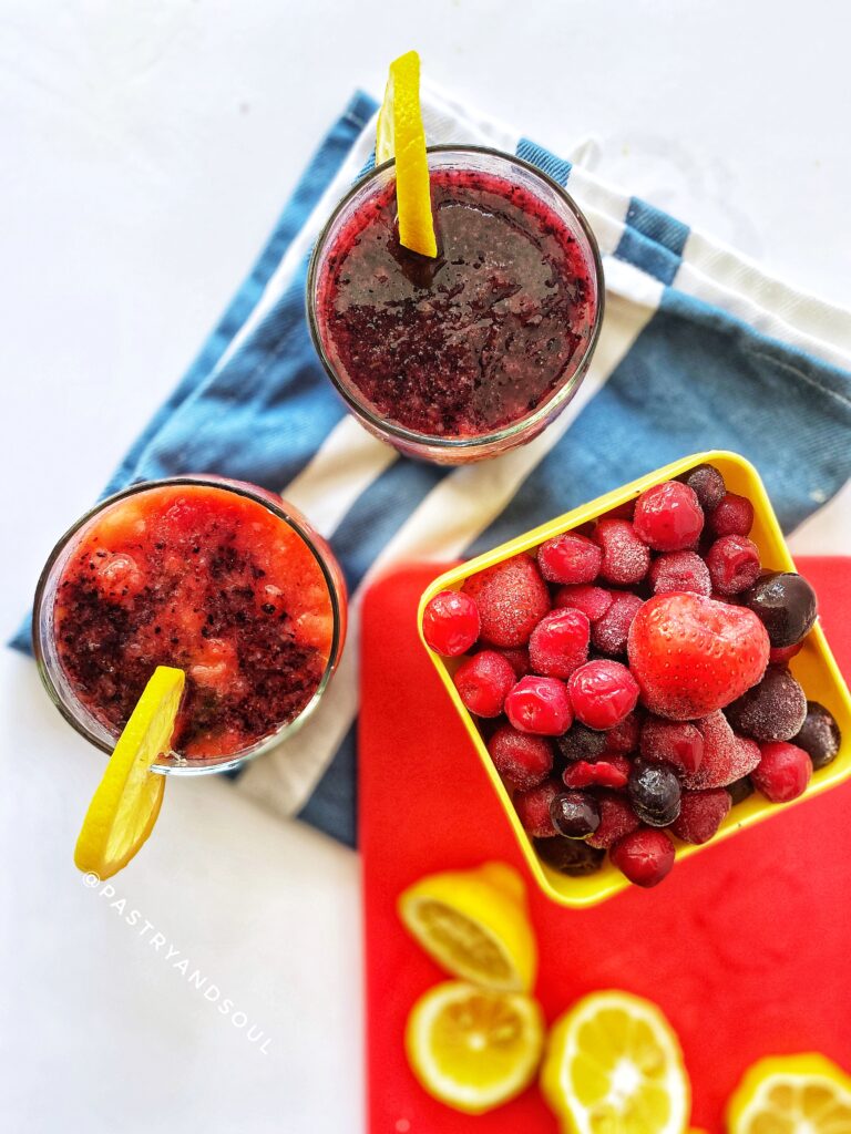 drinks in a glass cup and a bowl of frozen berries